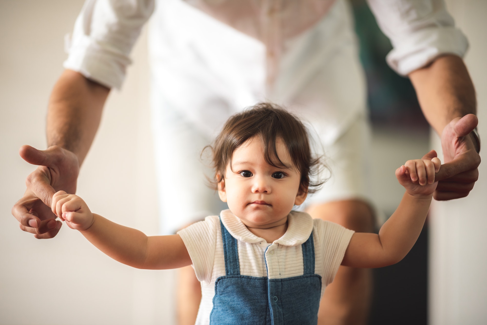 cute toddler little child family concept baby learning to walk with father and mother to help care